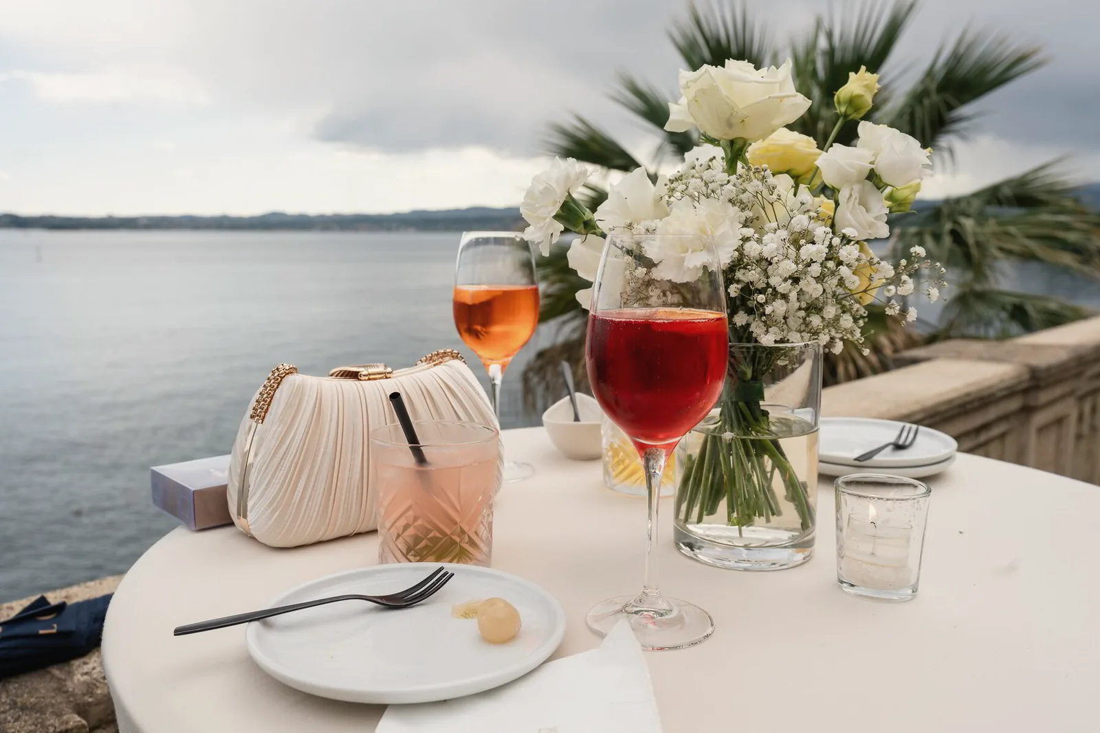 Spritz cocktails and white flowers on a terrace table above the lake