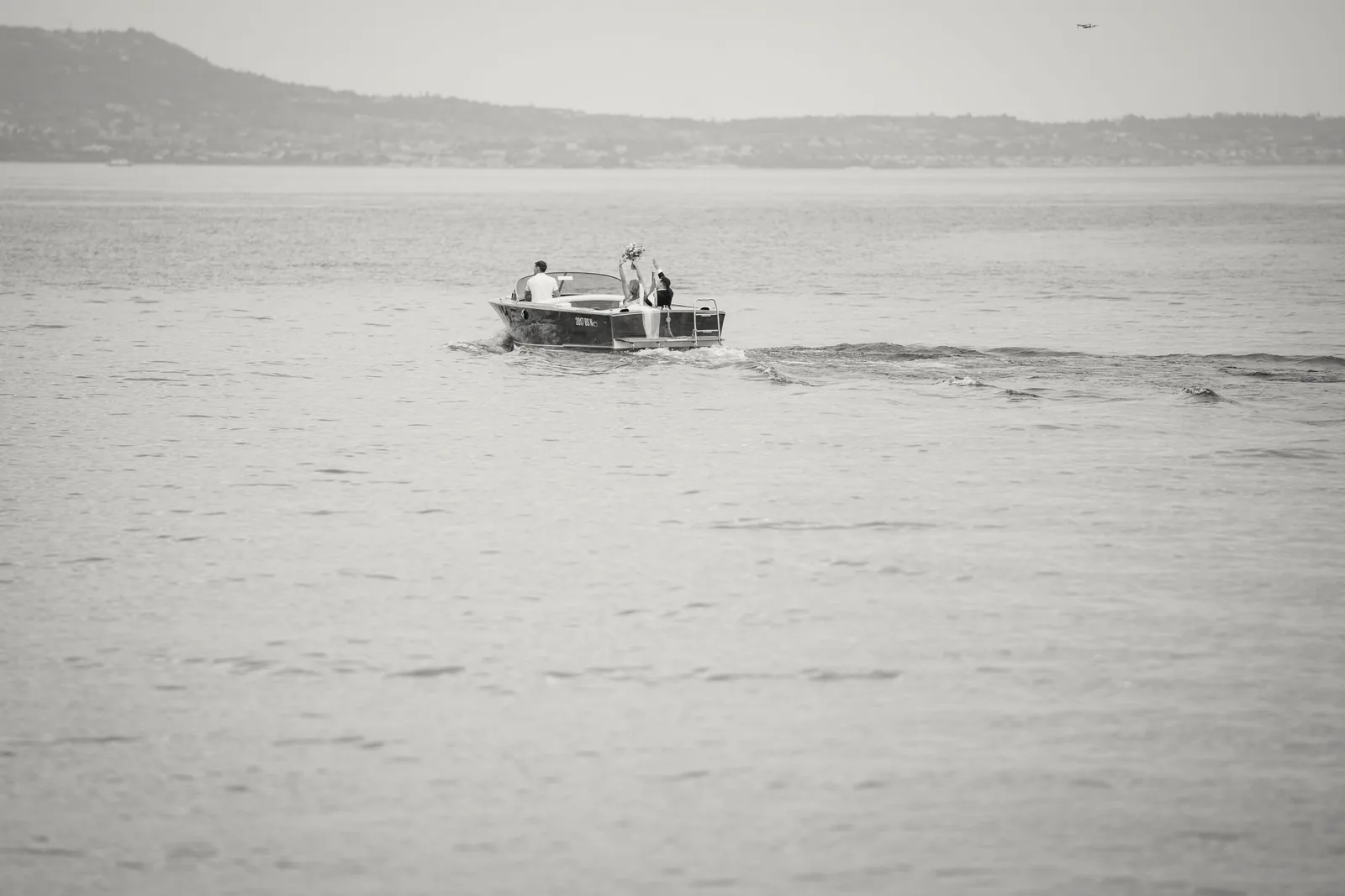 A small wooden boat crosses a wide, pale lake
