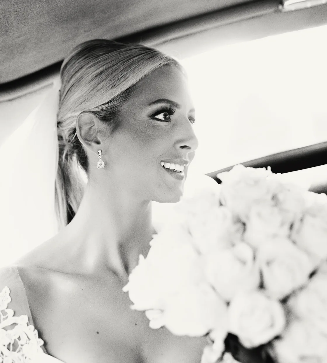 Black and white portrait of a smiling bride holding white roses