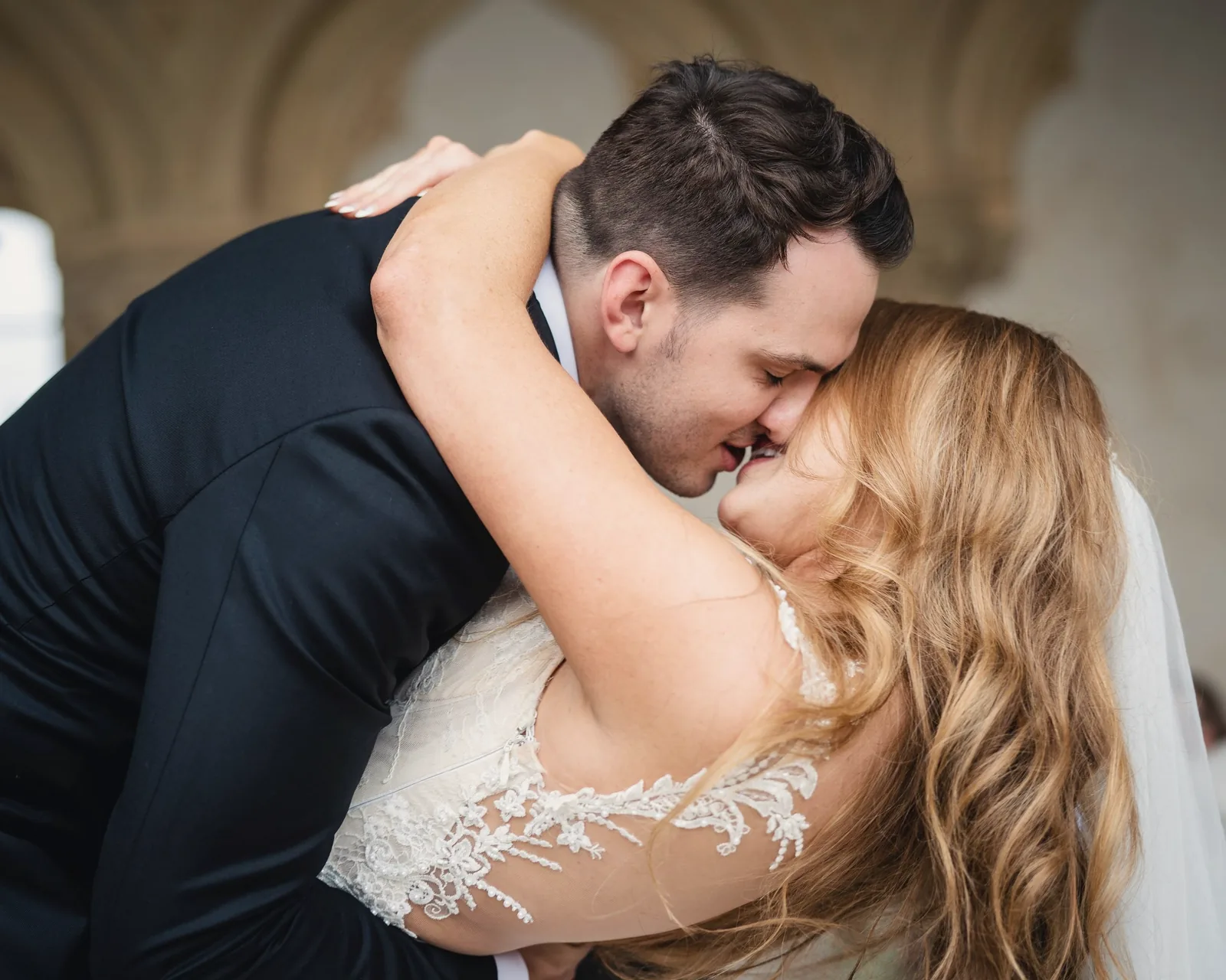 A groom pulls the bride into a laughing embrace