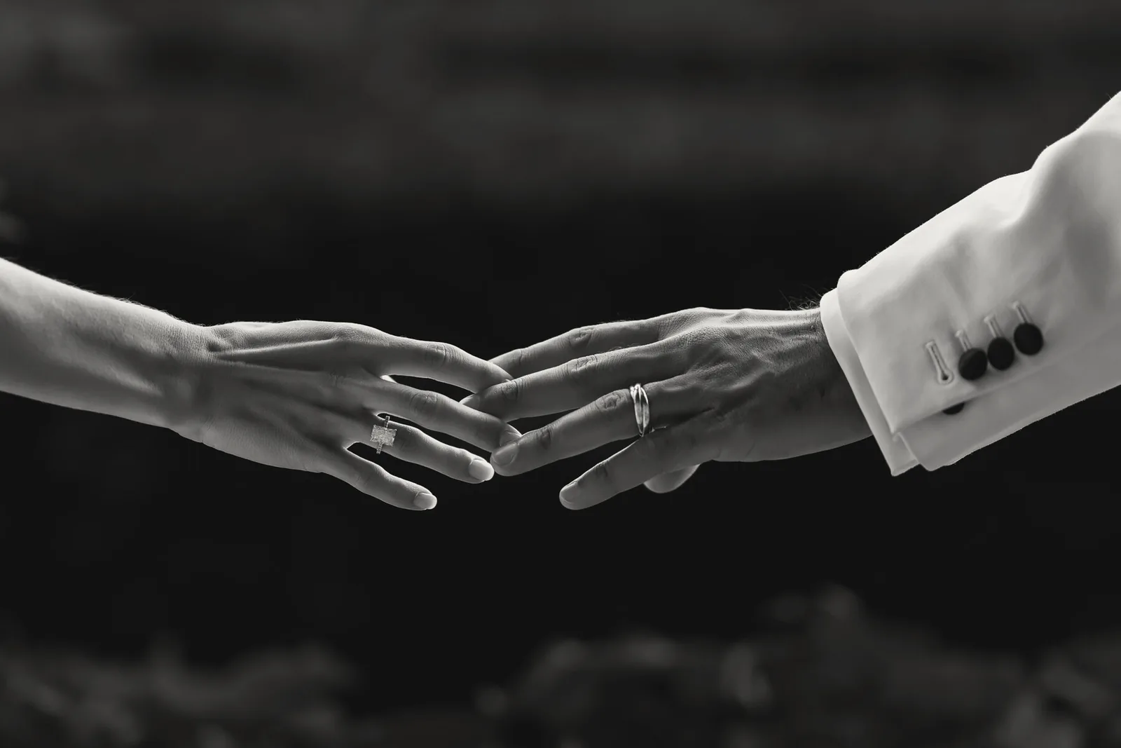 Two hands reach towards each other against a dark background