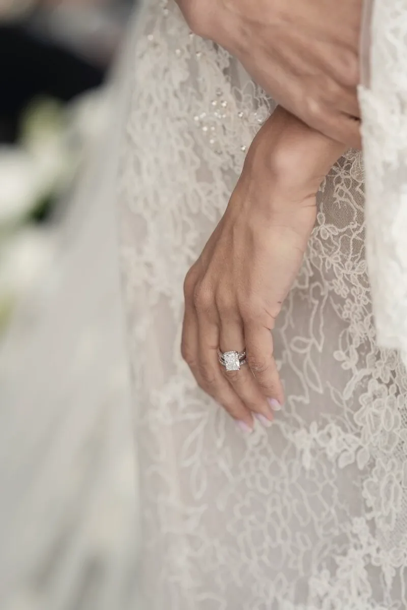 Close-up of a bride's hand resting on the lace of her gown