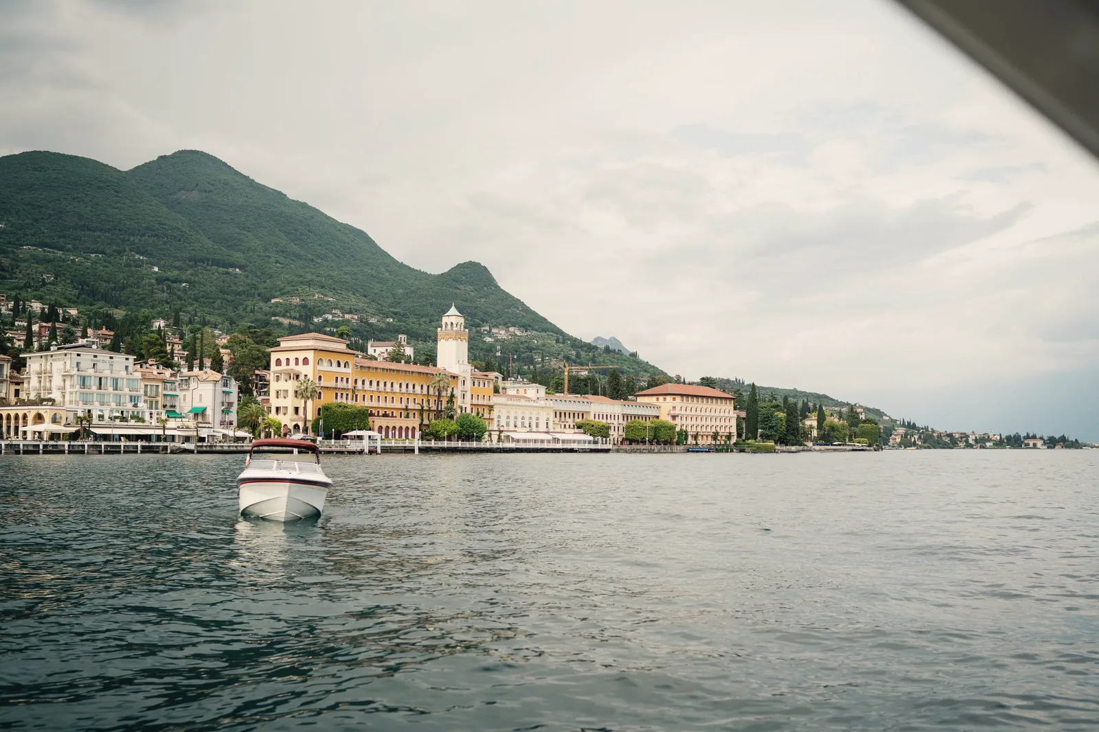 A pastel lakeside town beneath mountains, seen from the water