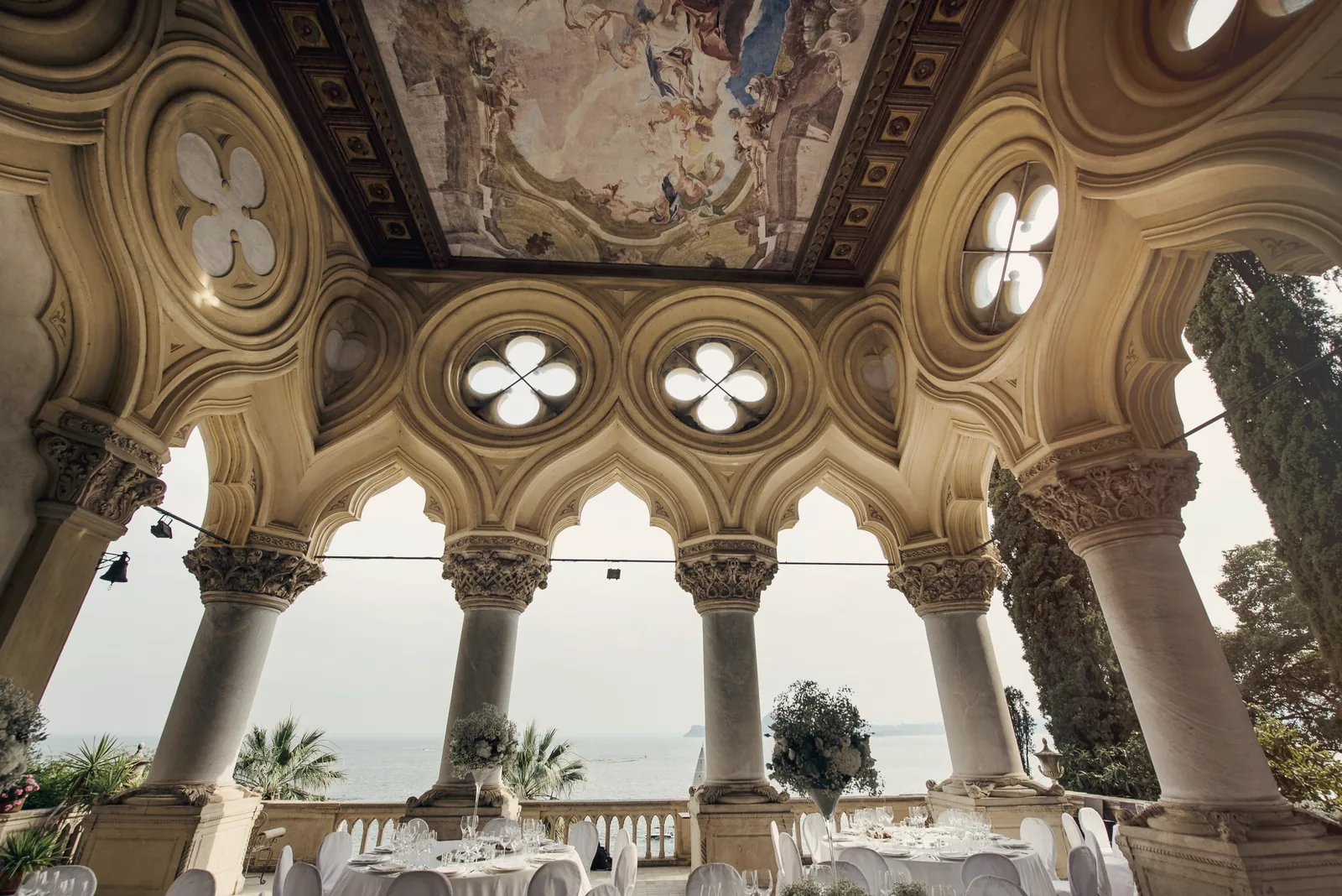 The painted ceiling and Gothic arches of a loggia, with the lake beyond