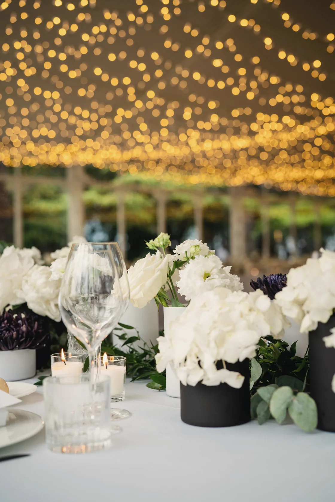 A reception table beneath strings of warm lights