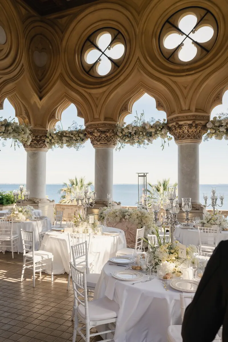 Wedding tables set with white flowers beneath a Venetian Gothic loggia overlooking the lake