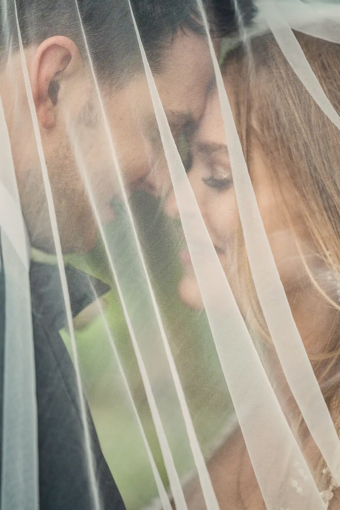A couple kisses behind a sheer veil